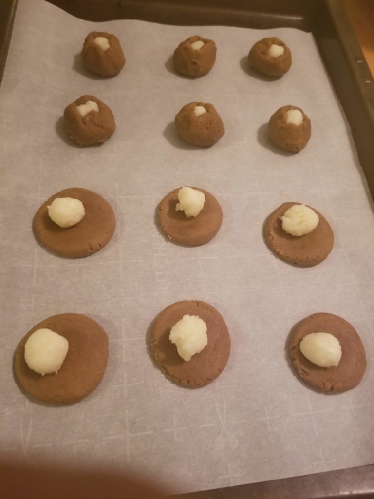 A cookie sheet with six unbaked balls of dough wrapped around cheese filling, and below that six with balls of cheese on flat dough circles
