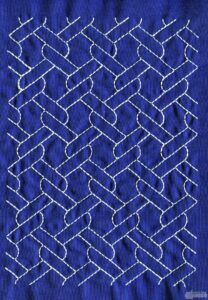 Blue fabric stitched in white with a pattern of outlined linked ropes